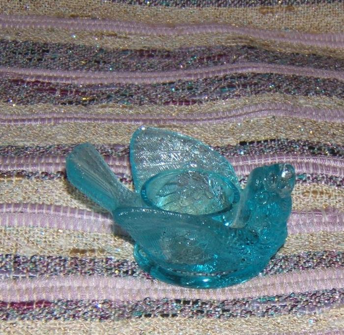 blue glass bird with berry in its beak